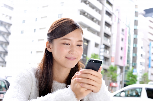 女性がスマホで面白そうに笑顔で作品を読んでいる写真