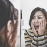 女性が鏡を見て異変に気がついている様子